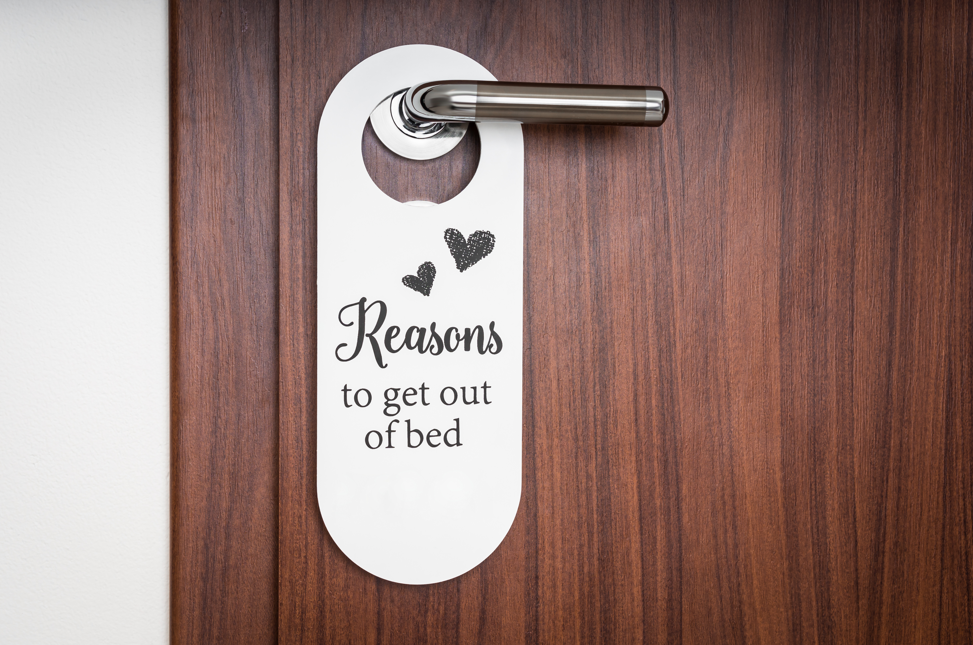 White door hanger with an invitation message on a dark wooden door