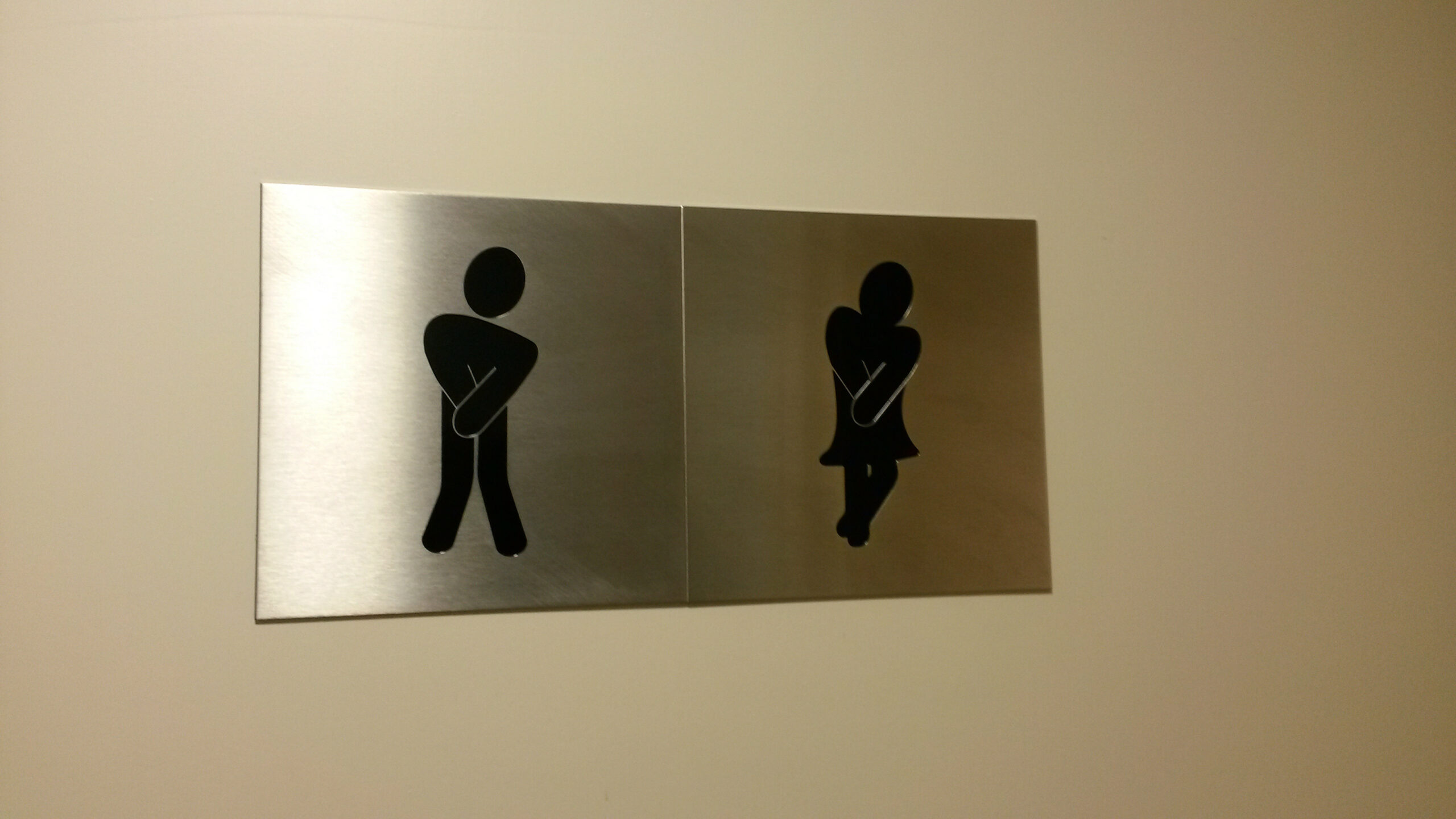 A humorous bathroom sign with stylized human figures 