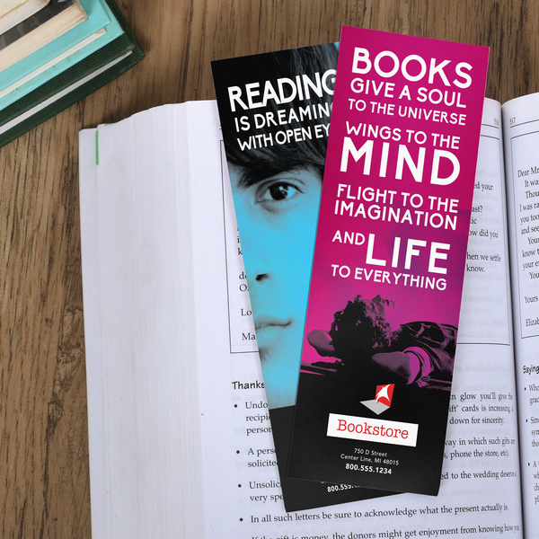 Custom printed bookmarks with colorful promotional designs displayed inside an open book