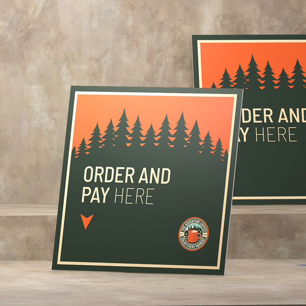 Square foam board sign with forest silhouette and “Order and Pay Here” text.