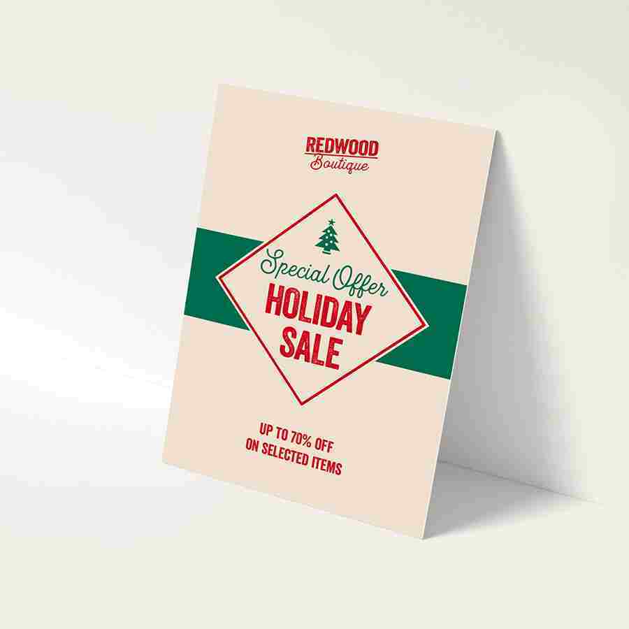 Printed holiday sale promotional poster propped on a white surface