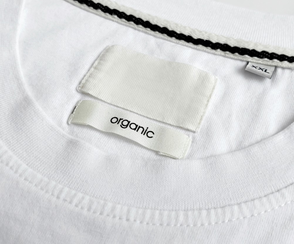 Close-up of a white t-shirt collar showing a printed fabric neck label