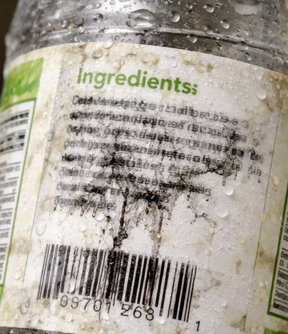 Wet plastic bottle with a damaged paper label