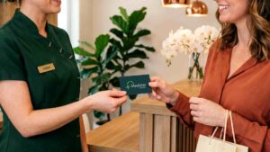 Receptionist handing card to customer.