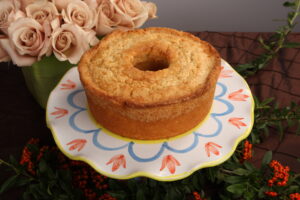 pound cake on a plate on a table with flowers in the background