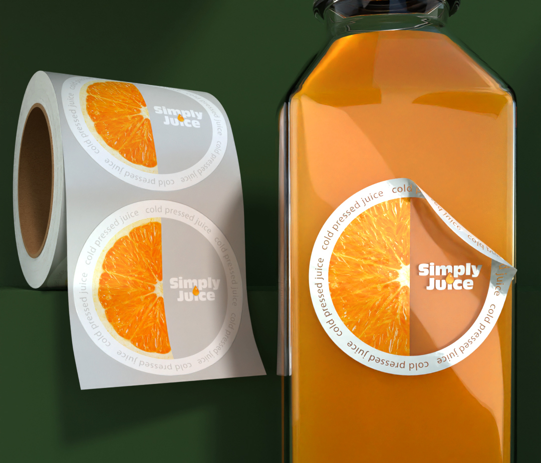 Roll of round juice labels displayed beside a juice bottle with an applied label featuring an orange slice design.